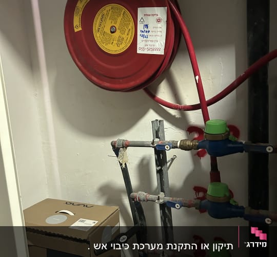 גלגלון כיבוי אש עם צינור אדום על הקיר